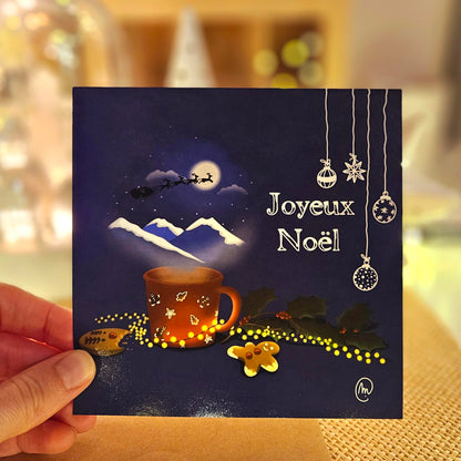 Carte de Noël représentant un chocolat chaud d’où s’échappe une fumée dans laquelle on aperçoit le traîneau du père Noël dans la nuit