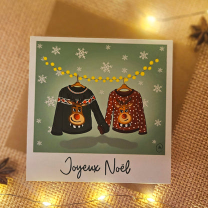 Carte de Noël représentant un couple de pull de Noël se tenant par la manche
